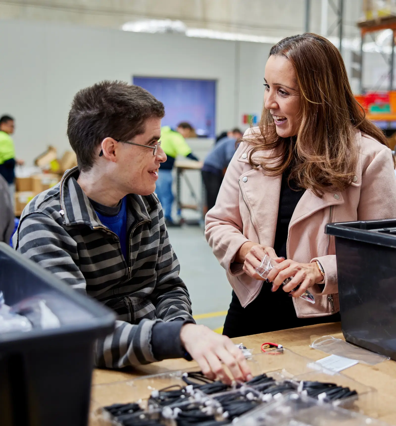 Two people at a workbench sorting packaged parts, laughing together