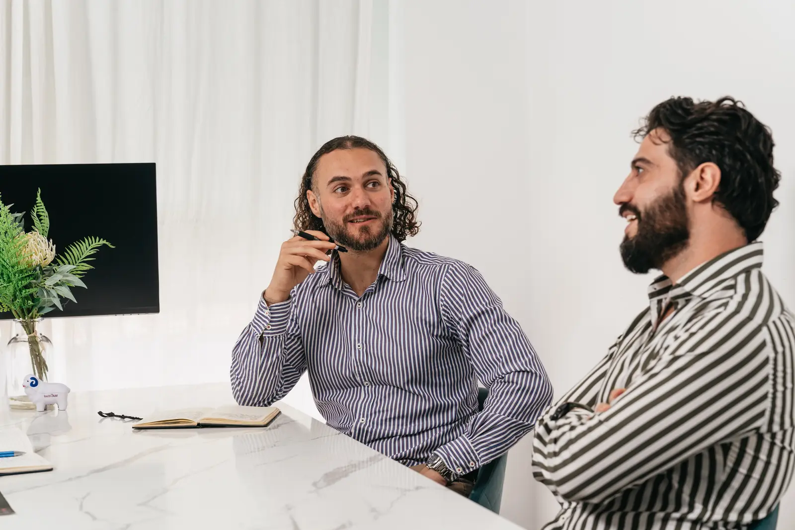 Rami Younes and Victor Khalil talking through a process at a meeting table